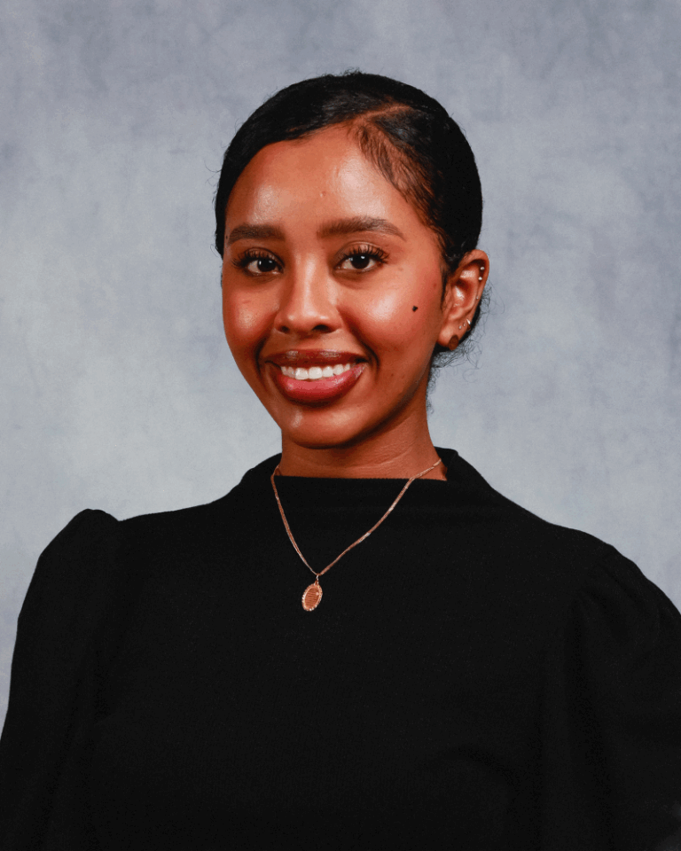 Woman in black suit smiling at camera.