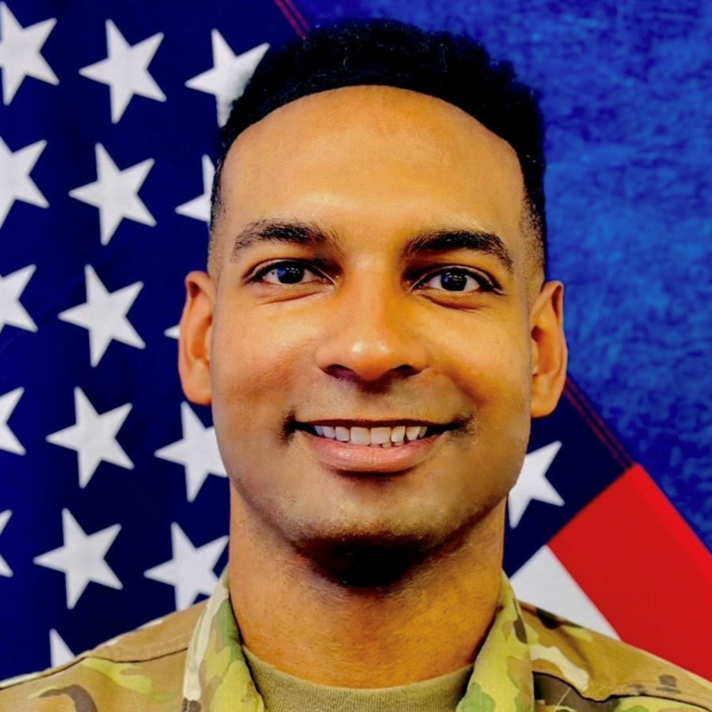 A man in military uniform, smiling and looking directly at the camera.