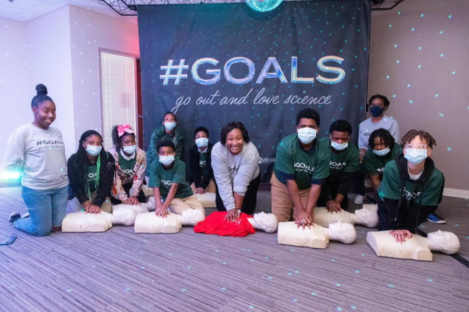 Group of people posing with large banner.