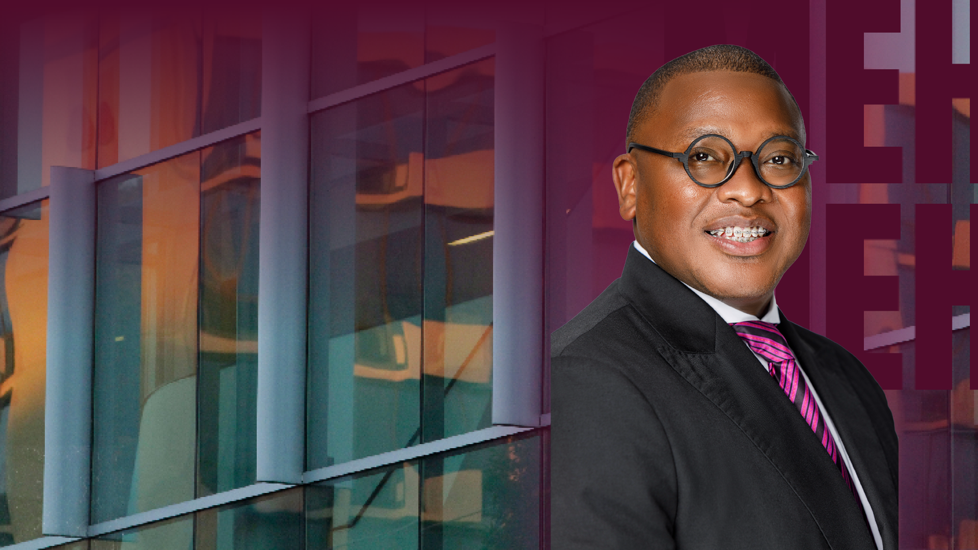 A man in a suit standing in front of a modern building.