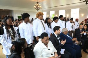 A group of people in white coats gathered in a room.