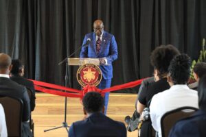 Man in suit at podium, speaking at event.