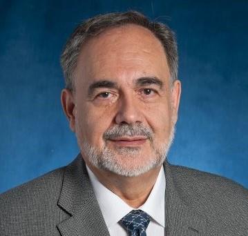 Man in suit standing in front of blue background.