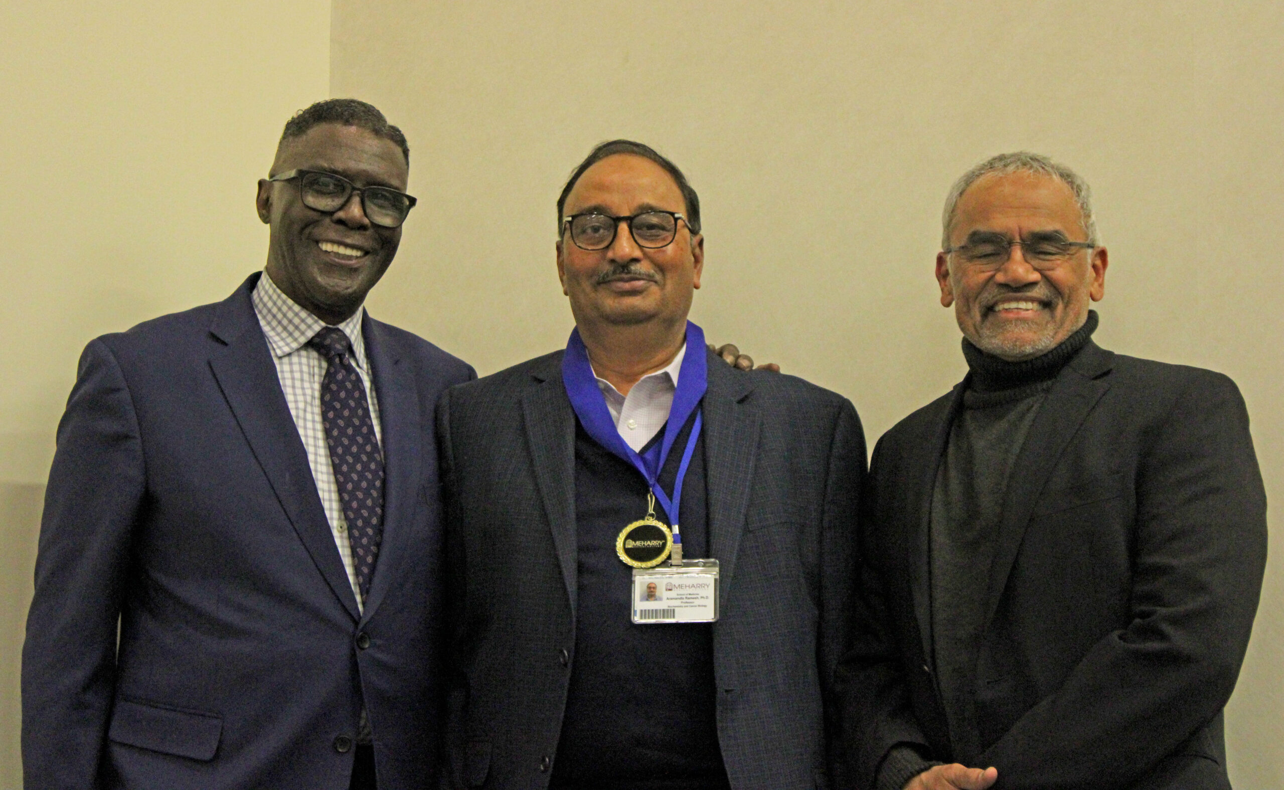Four men in suits standing together, smiling.