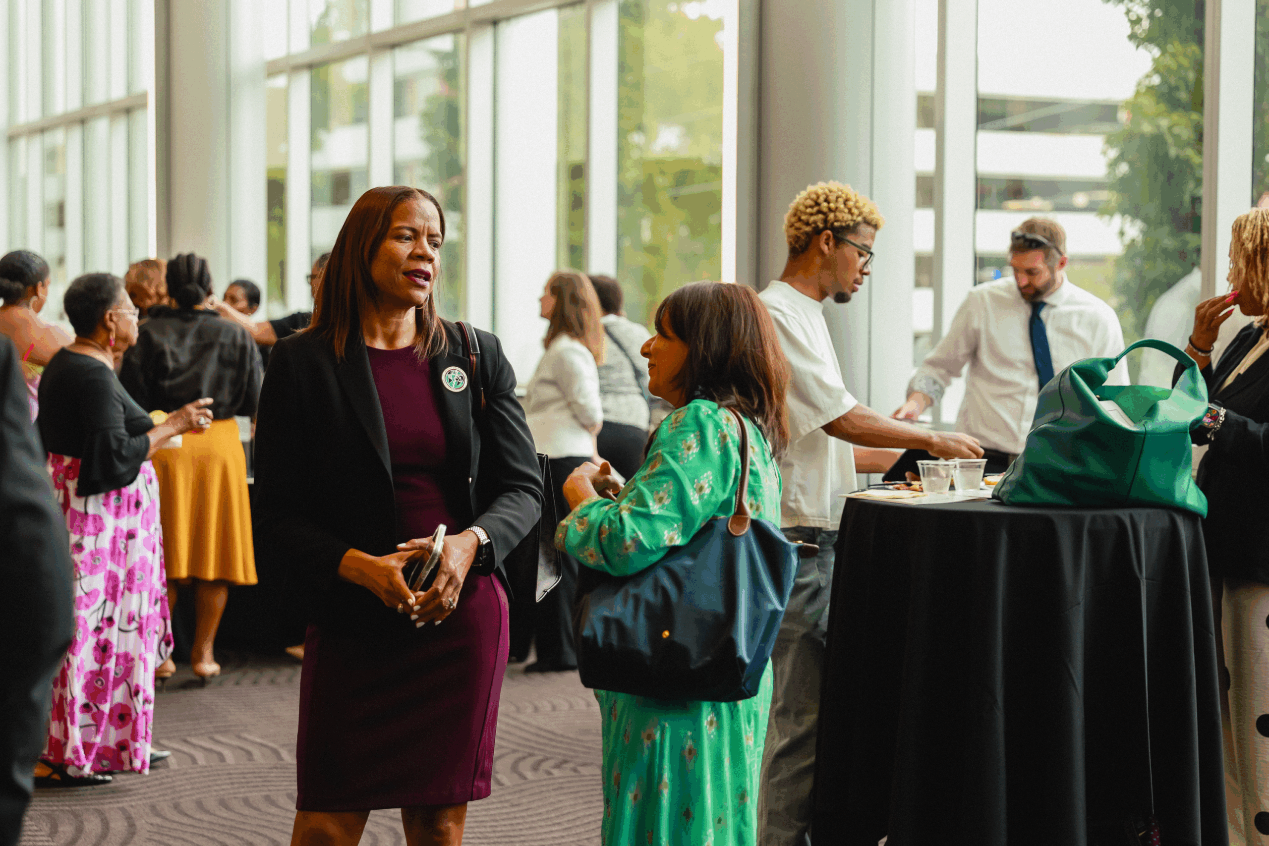 A woman in a purple dress stands amidst a crowd of people at an event.