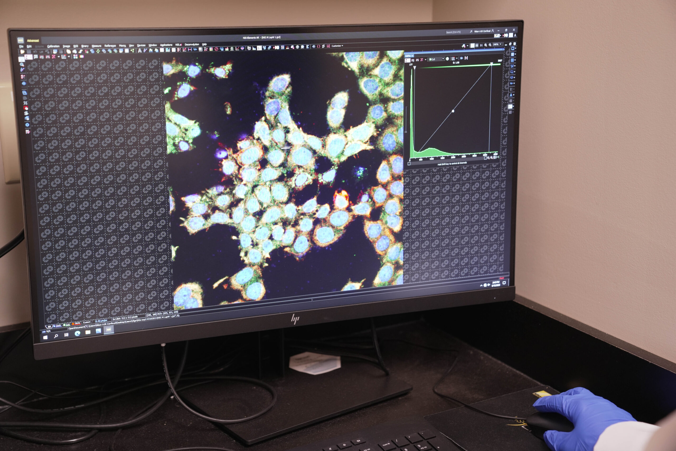 Computer monitors displaying scientific data, with a person in background.
