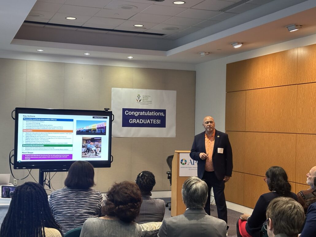 Man standing at podium in front of presentation screen.