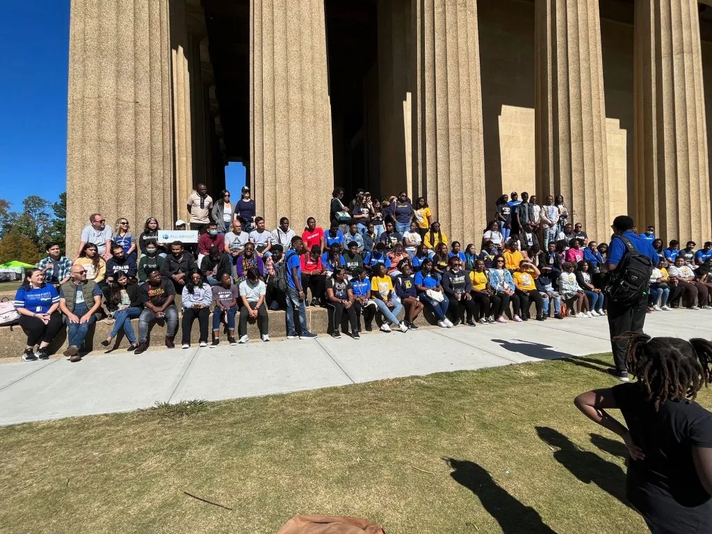People posing in front of a statue of liberty replica.