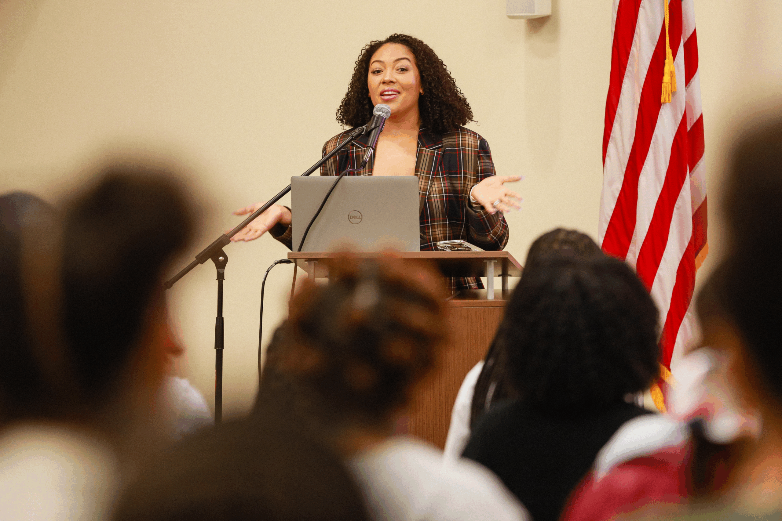 A woman speaking at a podium in front of an audience.