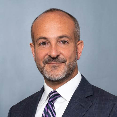 Man in suit, smiling, posing for portrait.