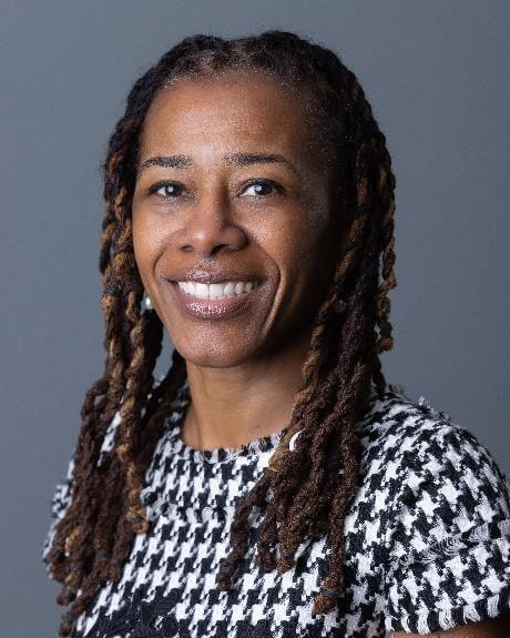 Woman with braided hair, smiling, posing for portrait.