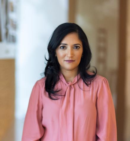 Woman in pink blouse standing in front of a wall.