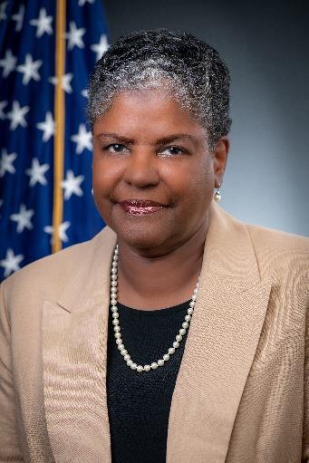 Woman in suit, smiling, posing for photo.