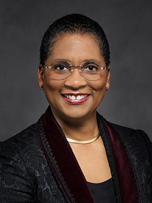 Woman in glasses, smiling, posing for portrait.