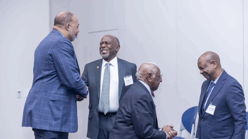 Men in suits shaking hands, one man in tie smiling.