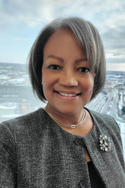 Woman in suit, smiling, posing for photo.