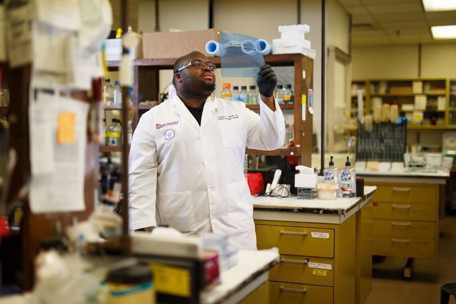 A scientist in a lab coat examining a microscope.