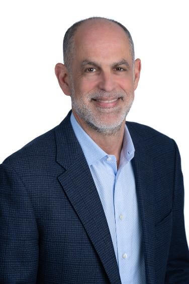 Man in suit standing against white background.