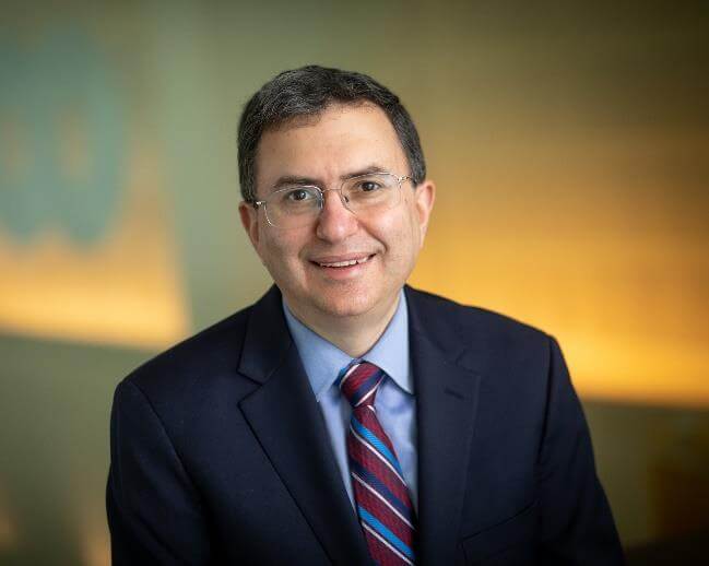Man in suit sitting in front of blurred background.