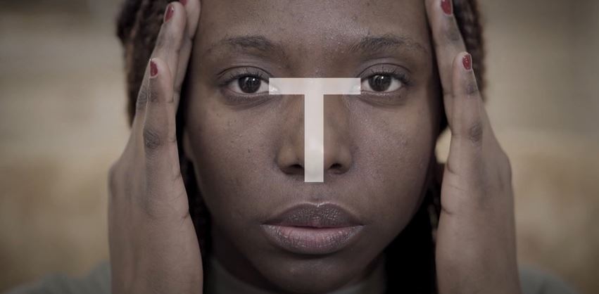 Woman with hands on head, looking up. Cross symbol on forehead.