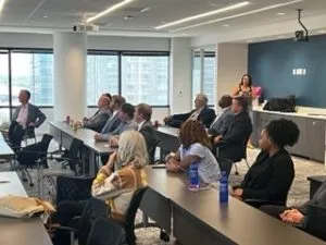 A group of people sitting in a conference room, facing a speaker.