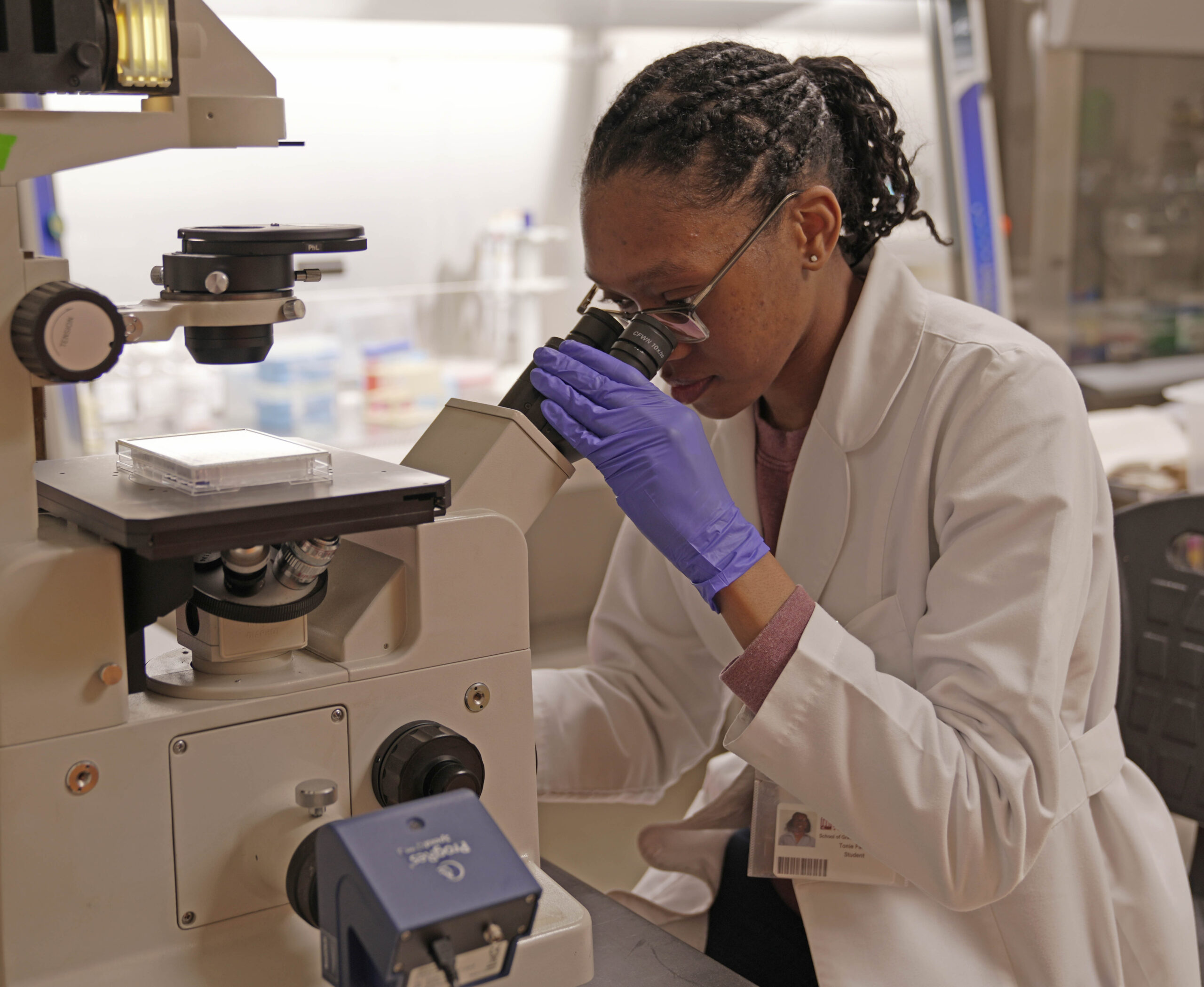 A scientist in a lab, examining a microscope.