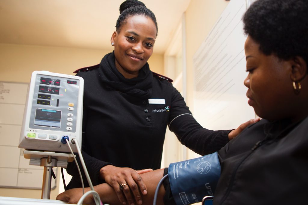 Nurse in white coat checking patient's blood pressure.