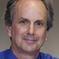 Man in blue shirt smiling at camera.