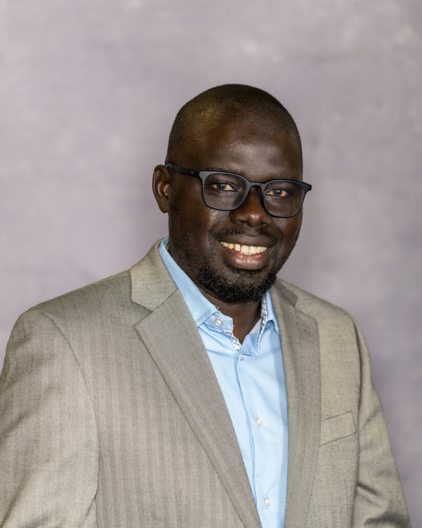 Man in suit standing, smiling, posing.
