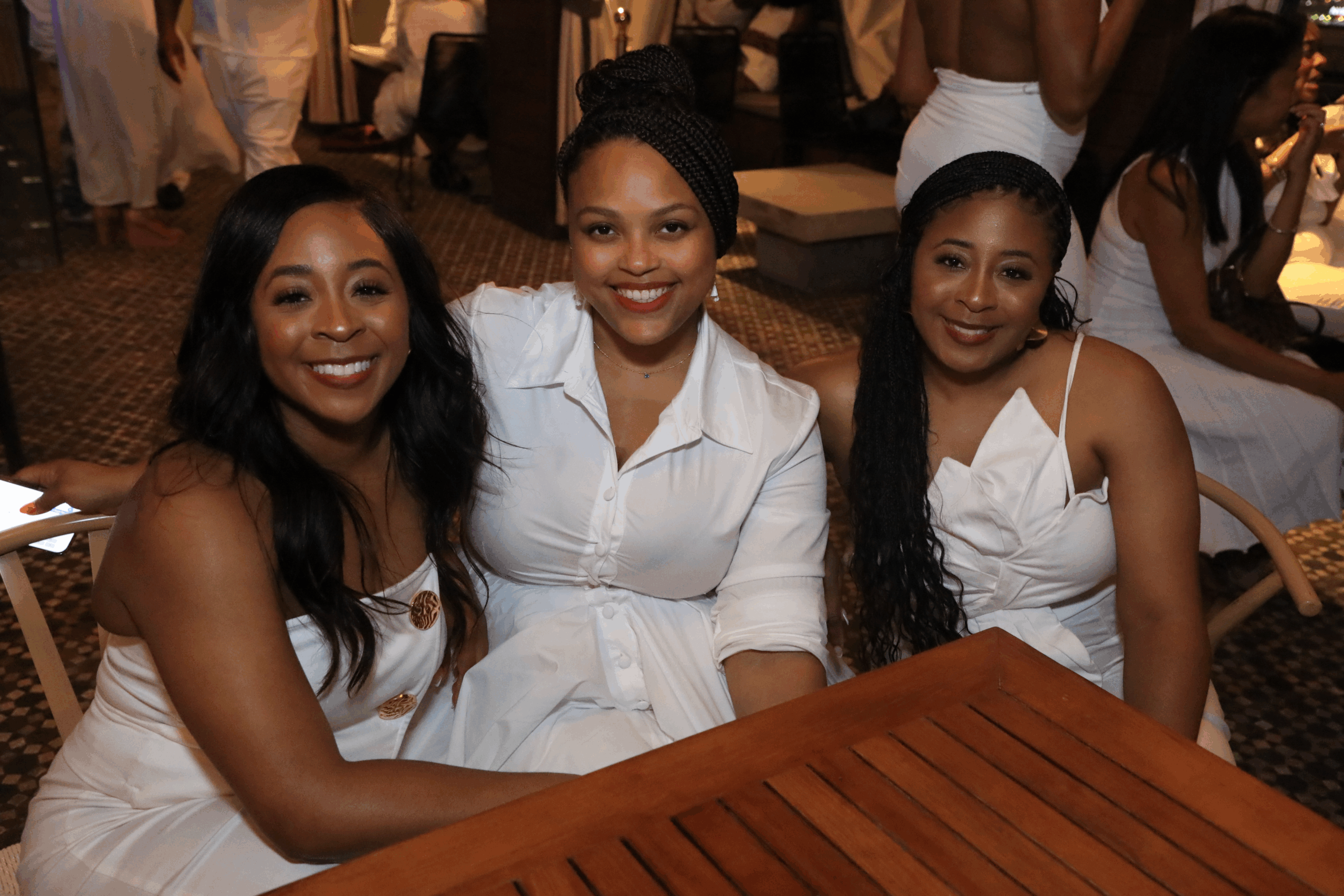 Three women in white dresses posing for a photo.