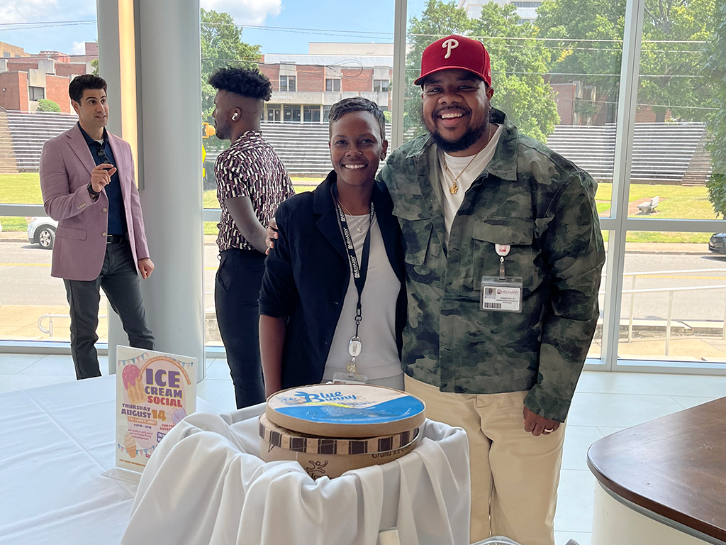 Man and woman posing with cake at event.