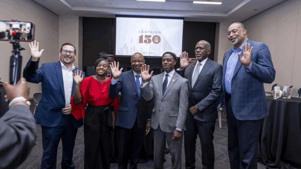 Group of people posing for photo, smiling, standing in front of a podium with a microphone.