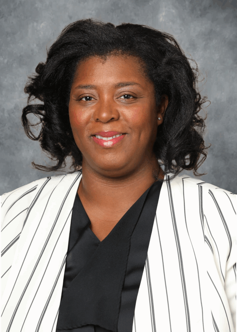 Woman in suit, smiling, posing for photo.