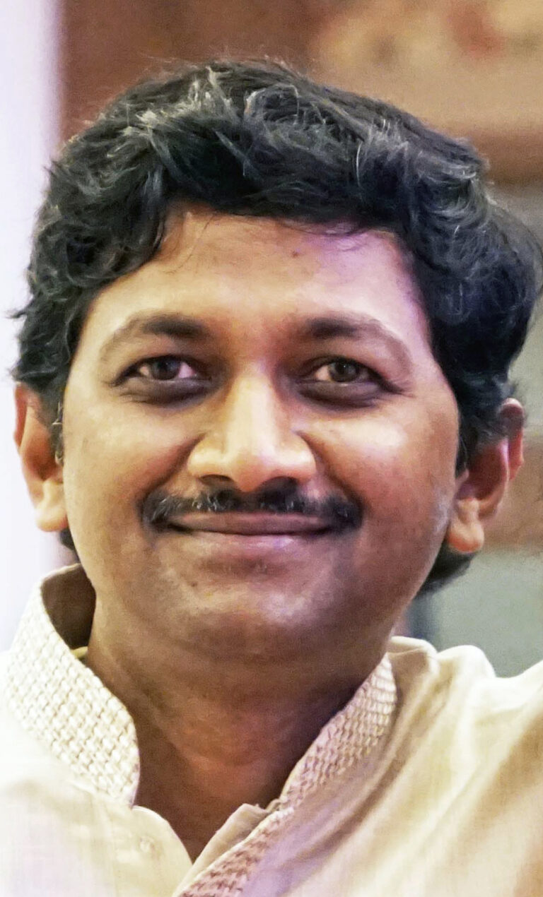 Man smiling at camera, wearing a suit.