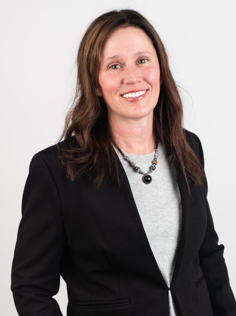 Woman in suit standing against white background.