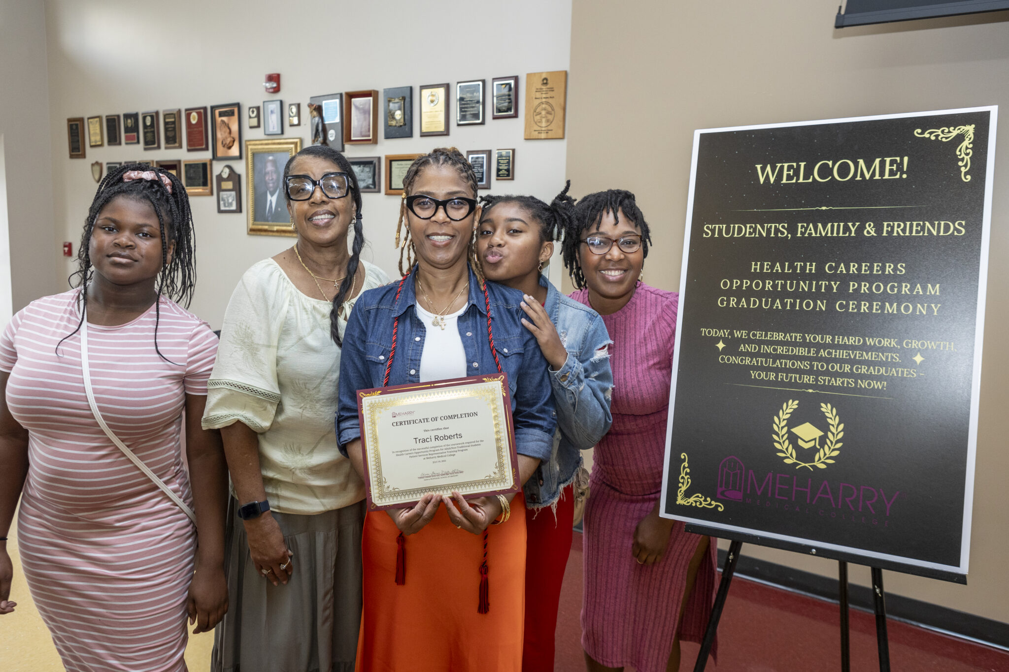 Group of people posing with a sign.