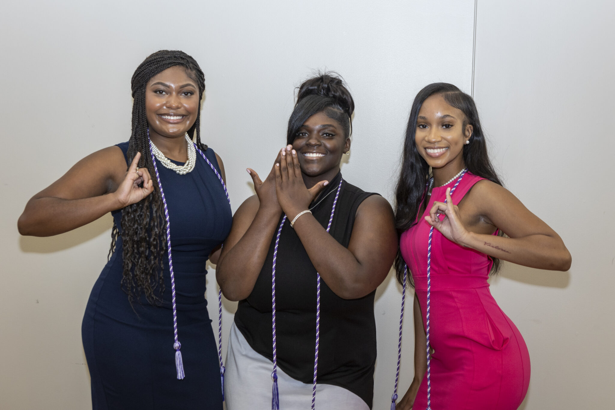 Three women posing for a photo, two wearing graduation caps, one with a peace sign.