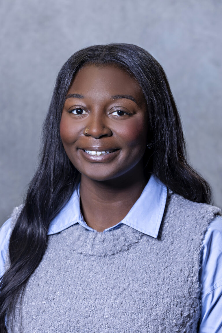 Woman in blue shirt and blonde hair posing for photo.