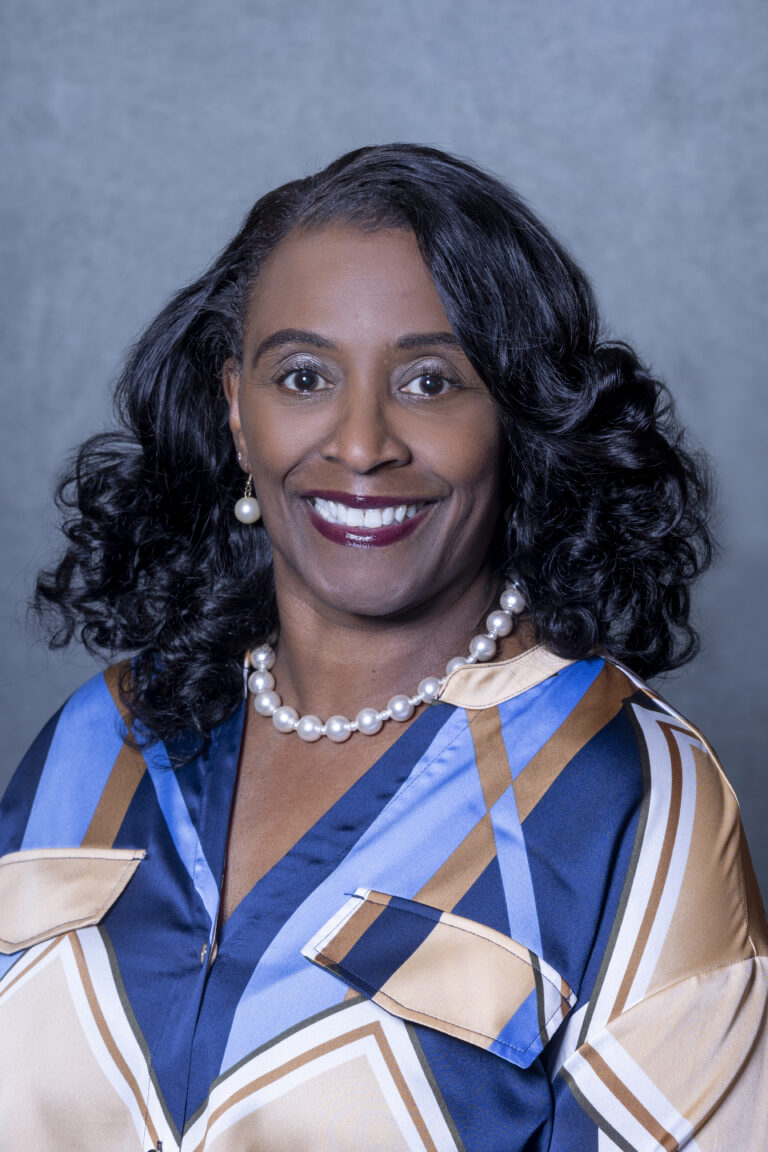 Woman in blue and white dress, smiling, posing for portrait.
