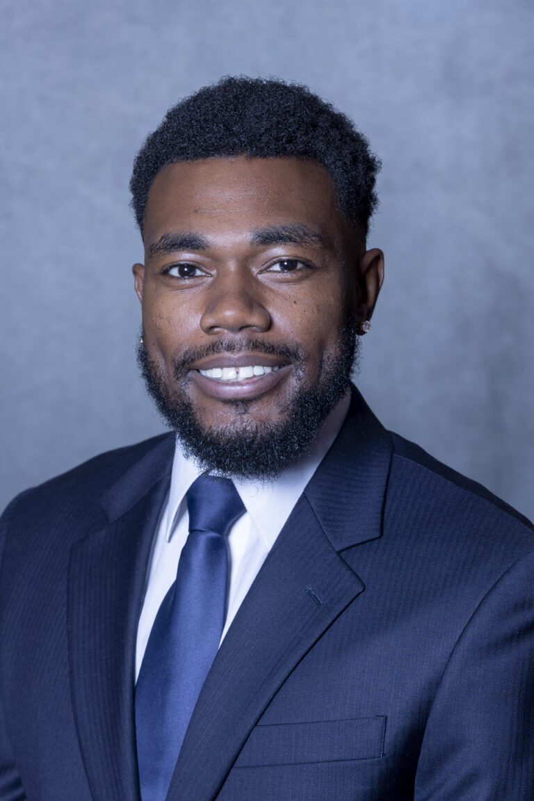 Man in suit smiling at camera.