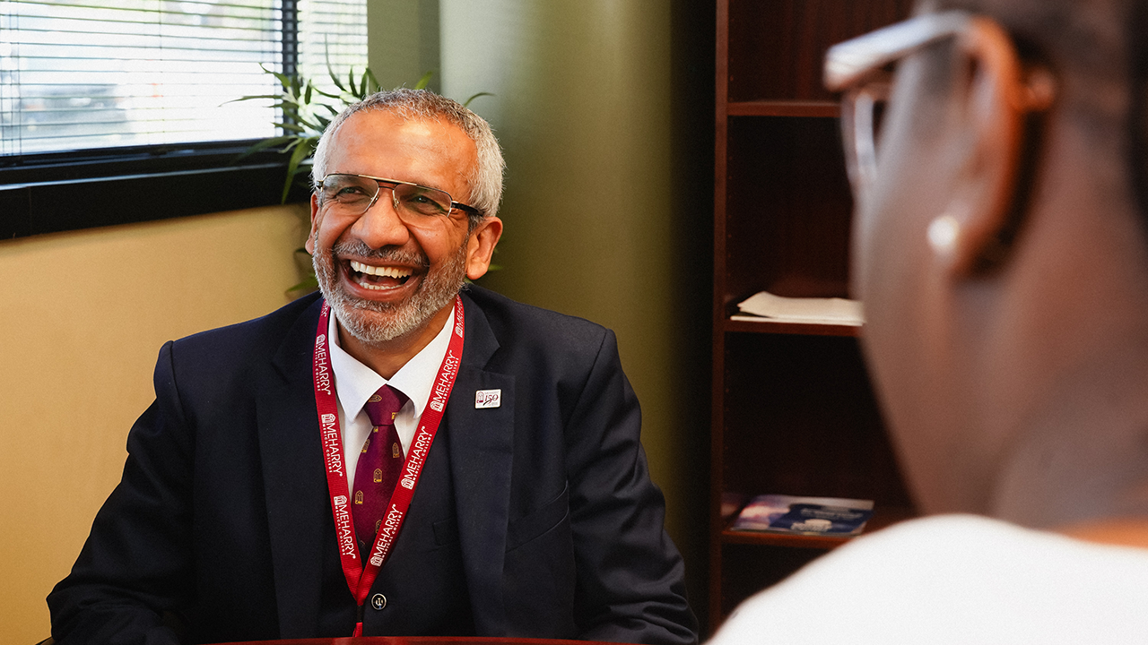 Faculty member smiles, student is in the foreground